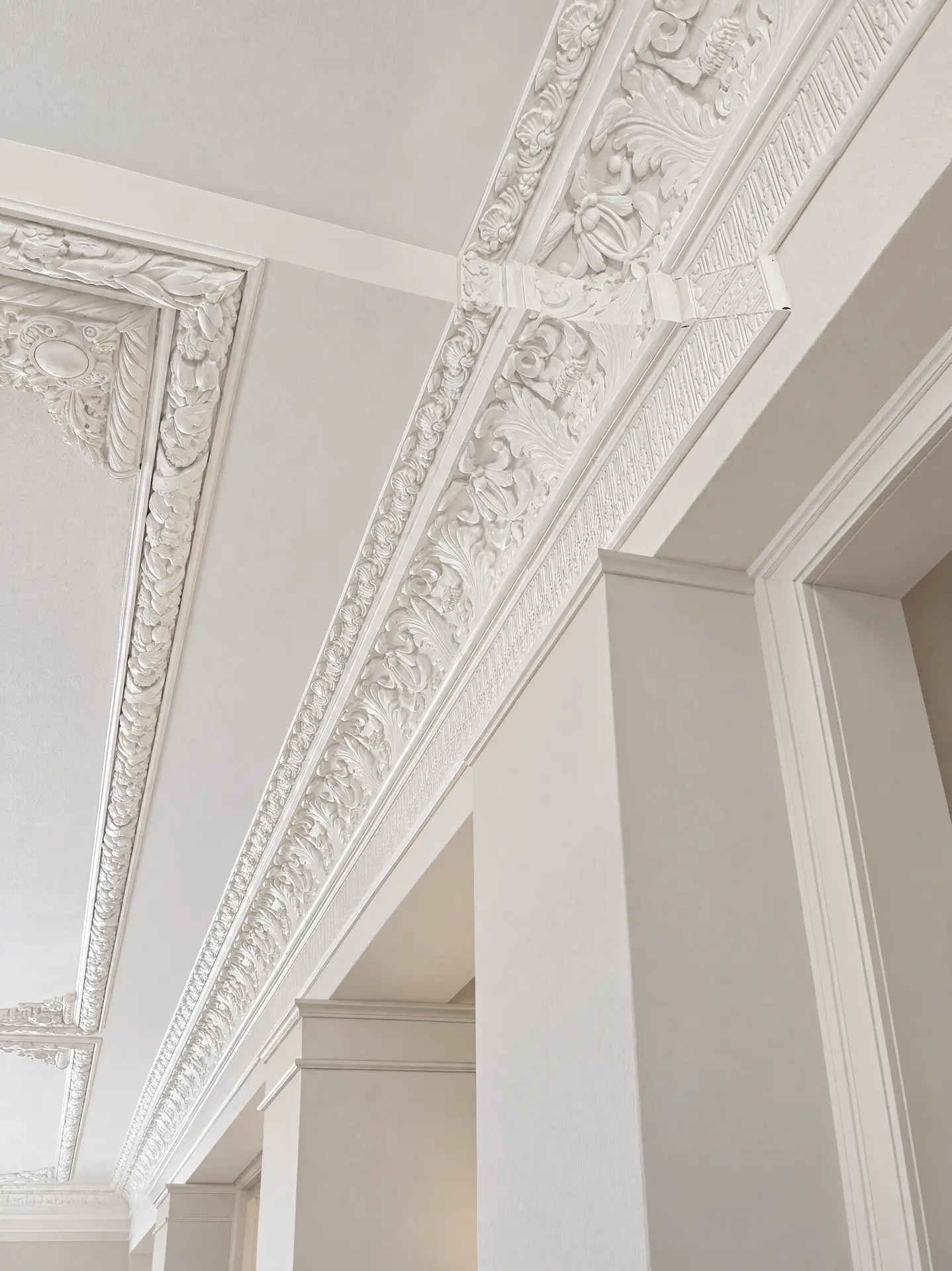 Ornate plaster crown molding installed along a ceiling corner in a bright interior
