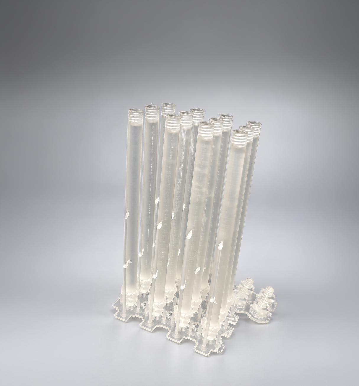 Clear SLA-printed tubes with threaded ends, still on their supports