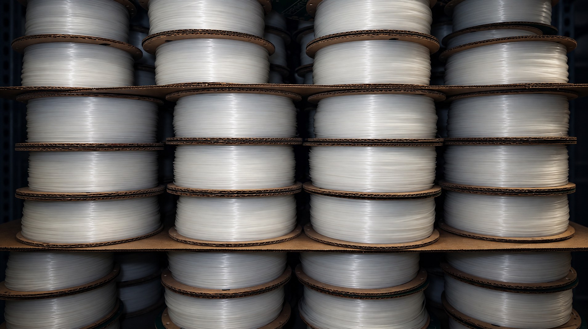Stacks of natural white filament spools on cardboard shelves in the Printerior shop