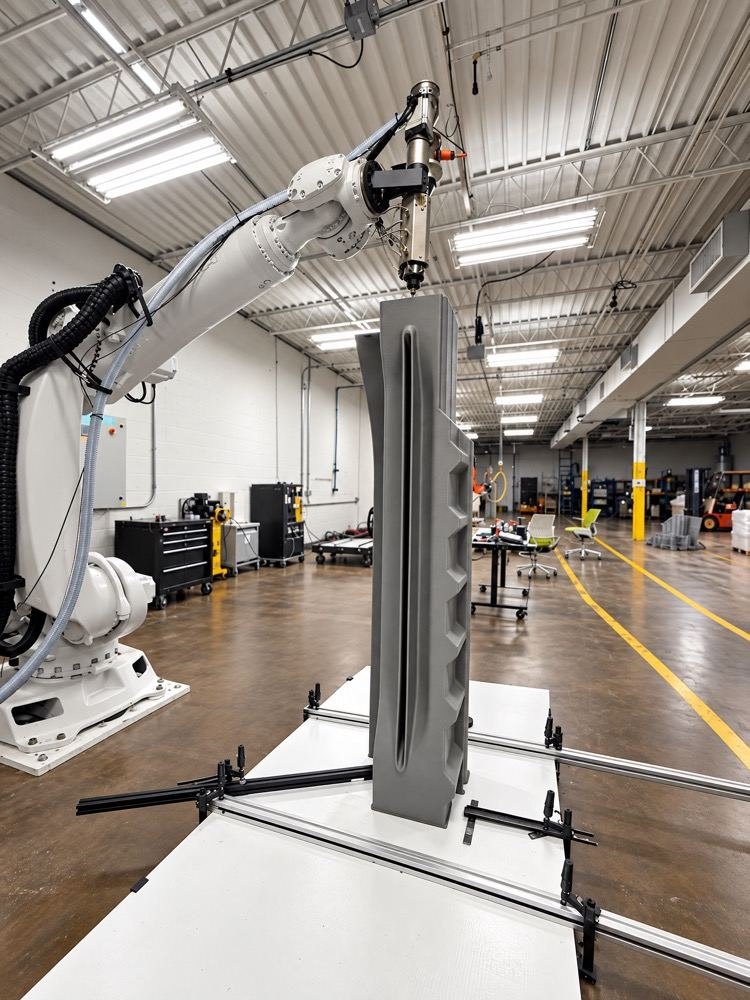 A white robotic print cell producing a large part