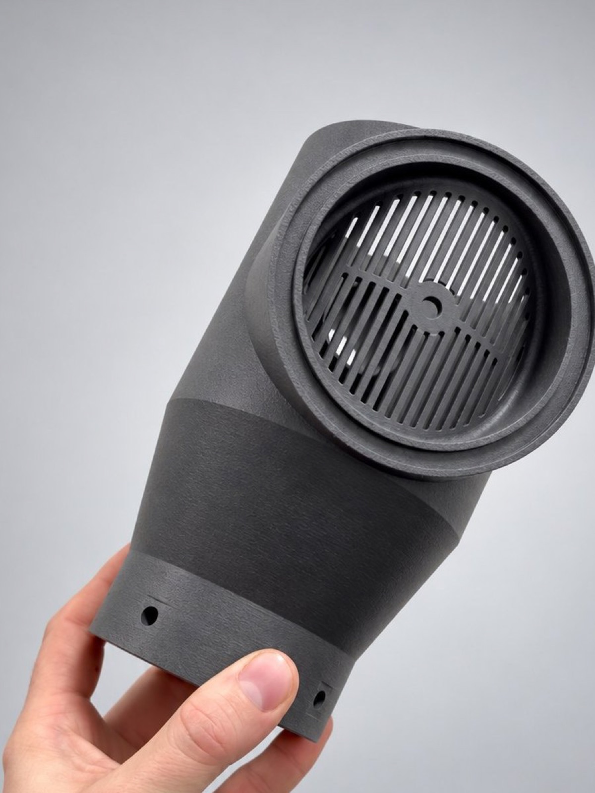Hand holding a grey nylon robotic-cell duct with a ribbed air opening