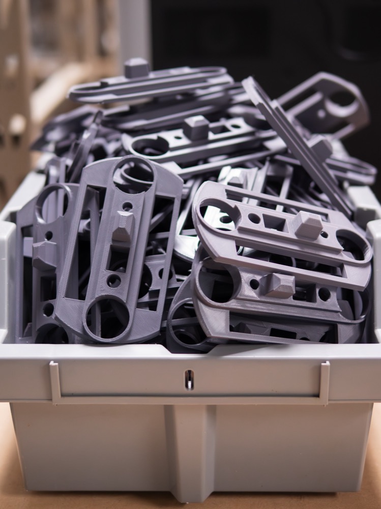 A bin filled with identical grey printed mounting plates